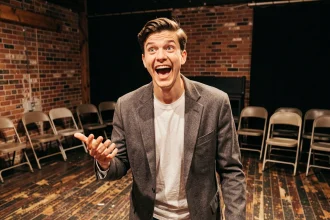 Jeune acteur masculin répétant un monologue comique sur une scène de théâtre intime en boîte noire